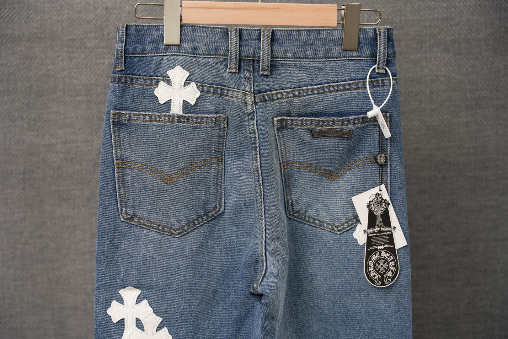 Blue denim pants with white cross patches and front pockets