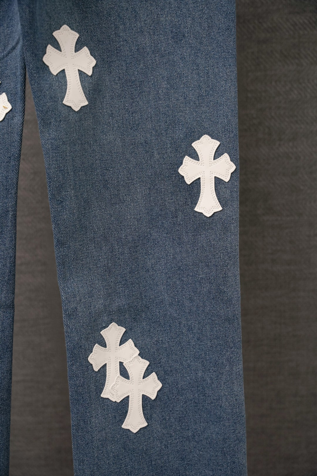Blue denim pants with three white cross appliques on the leg