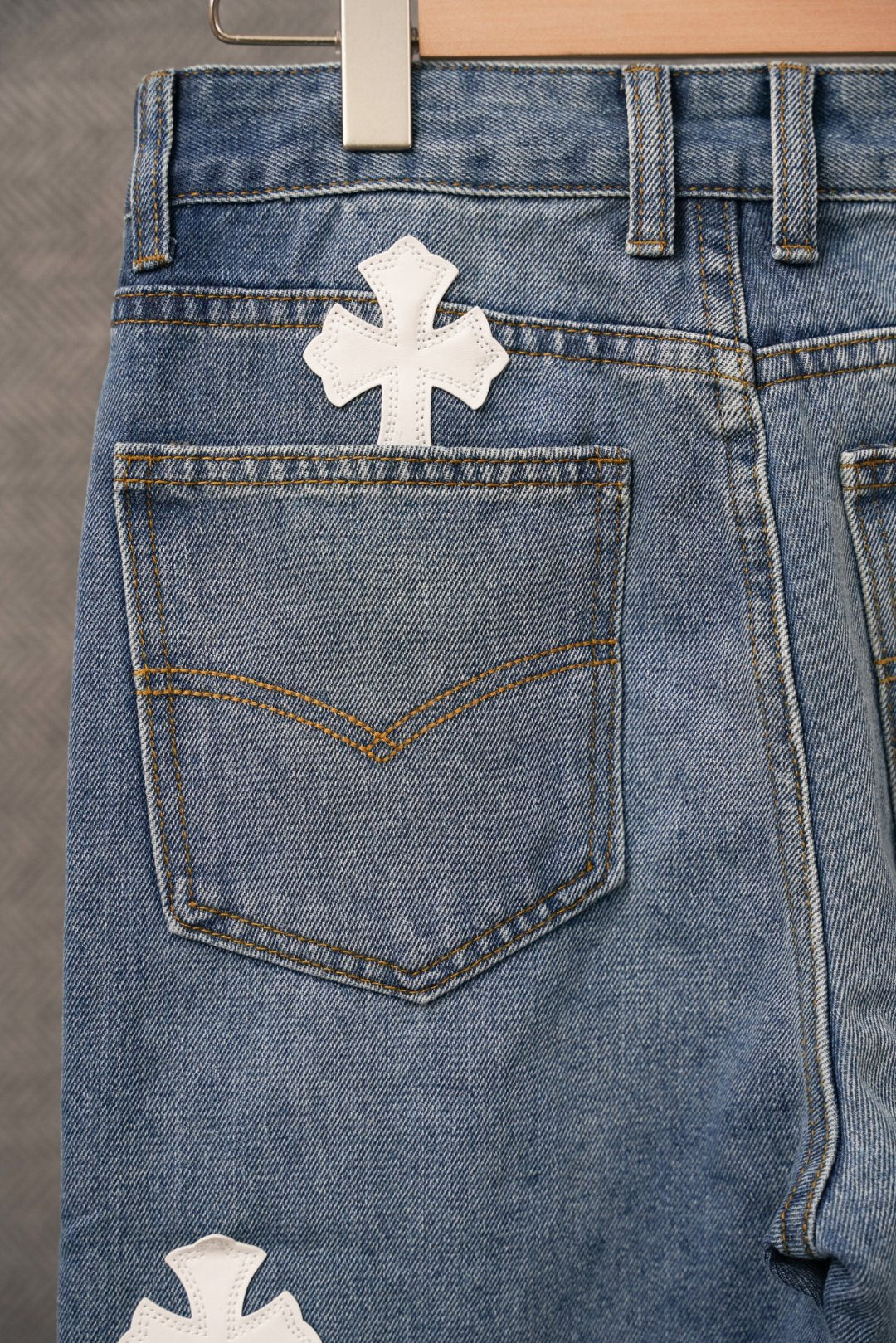 Blue denim pants close-up: white cross patch and stitched front pocket