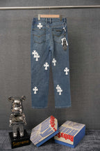 Blue denim pants with repeating white cross patches, relaxed straight fit.