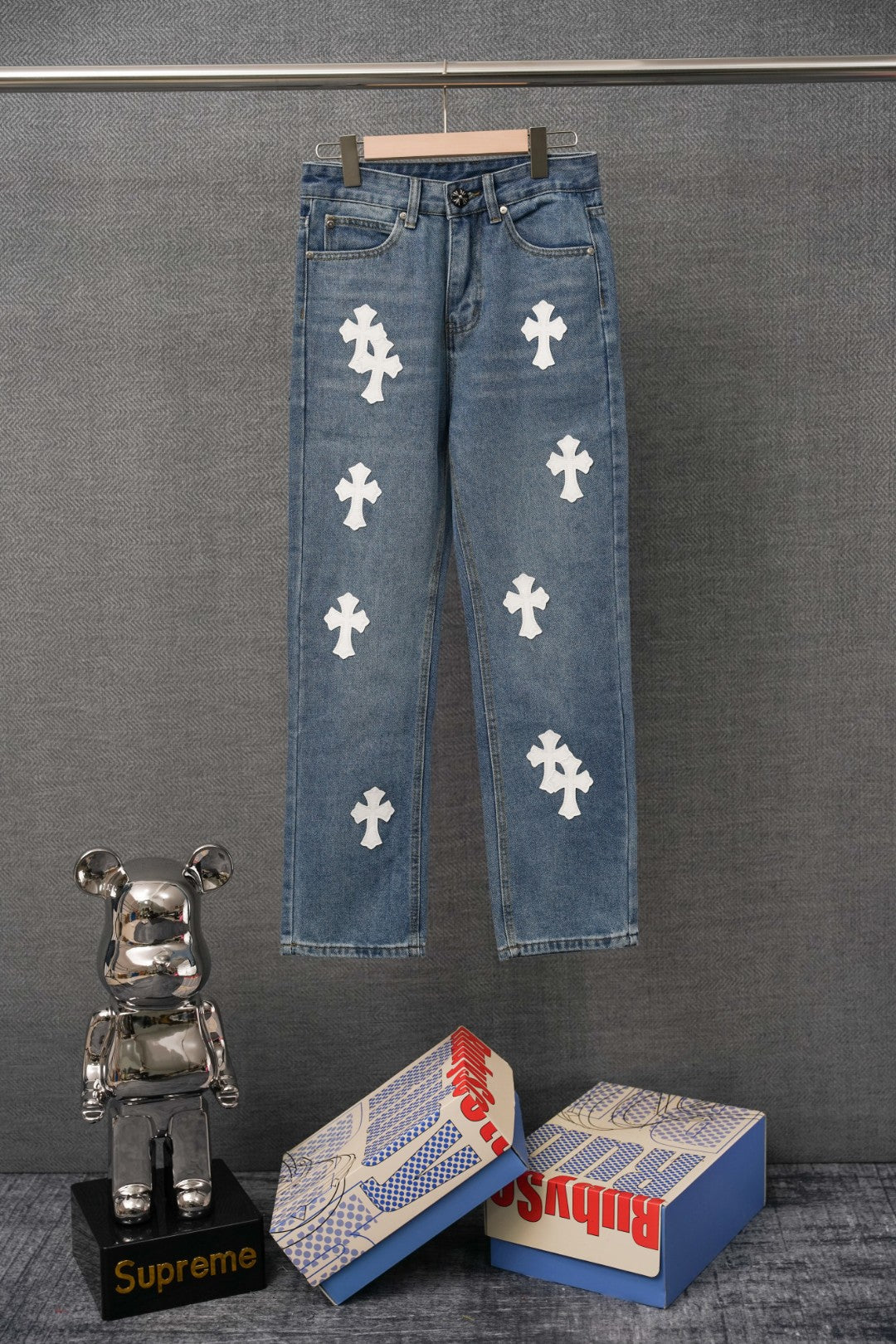 Blue denim pants with repeating white cross patches, button fly, straight leg.