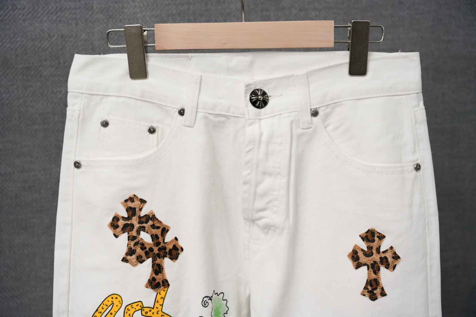 White denim pants close-up of waistband, front pockets, and leopard-print cross