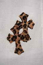 White pants featuring a leopard-print cross applique patch