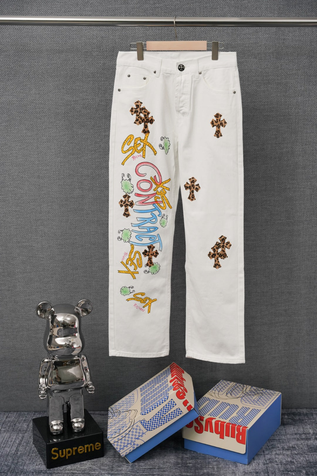 White pants with leopard-print cross patch and multicolor graphic embroidery