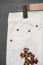 White denim pants with button fly and small leopard-print cross applique