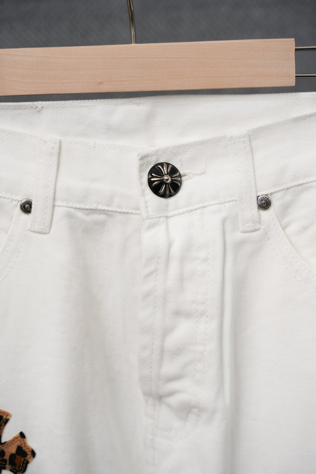 White denim pants close-up of front button and belt-loop area