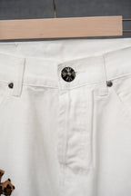 White denim pants close-up of front button and belt-loop area