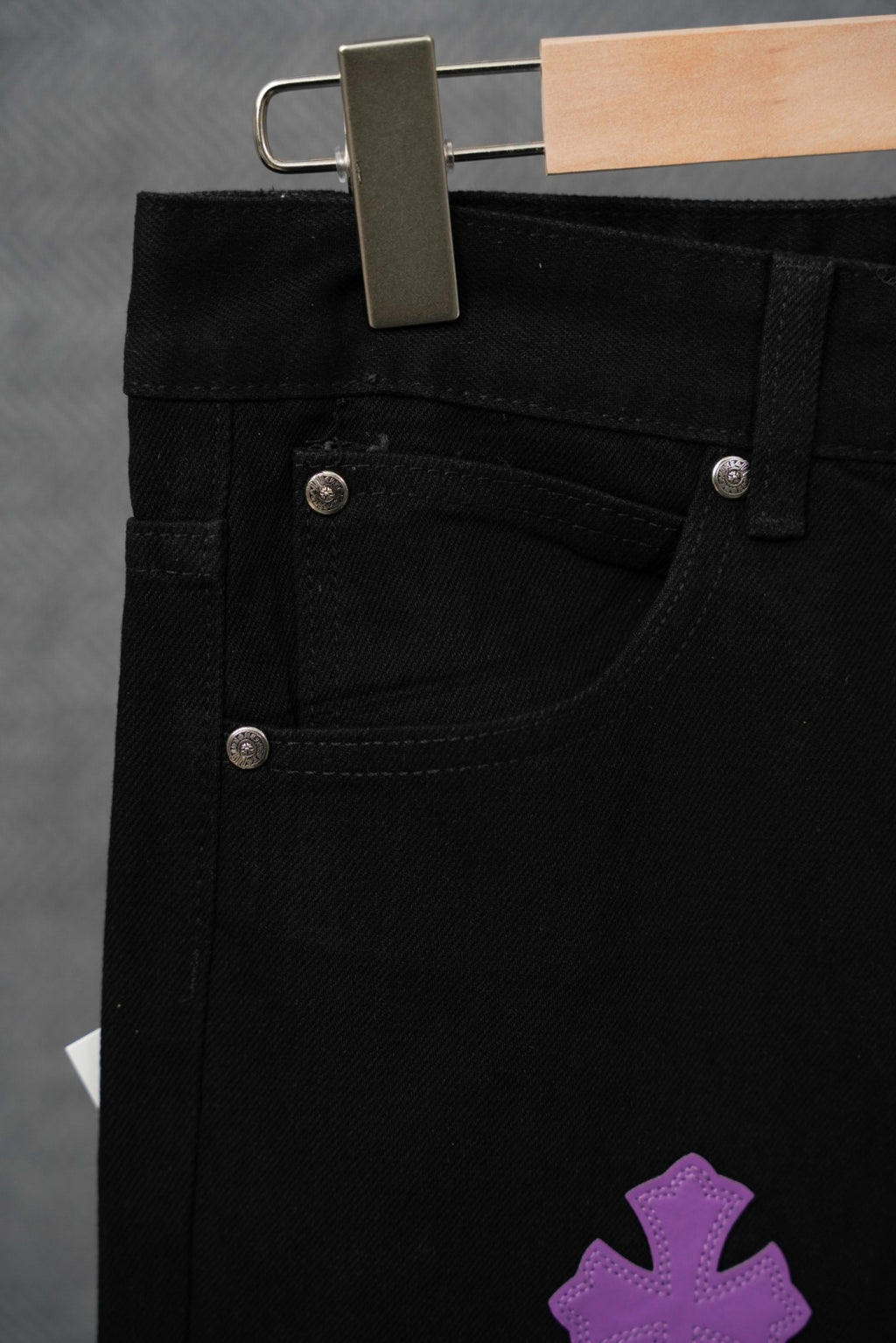 Black pants with front button closure and curved pocket seam detail.