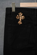 Black pants with central purple-gold cross patch, front pocket and waistband detail.