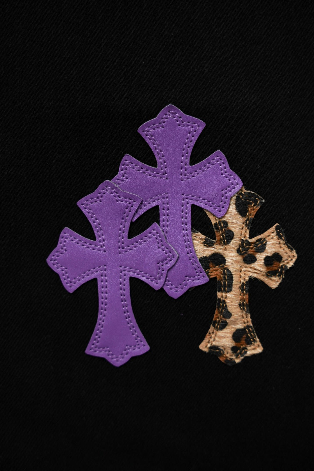 Black pants close-up: large purple cross patch with leopard-pattern center.