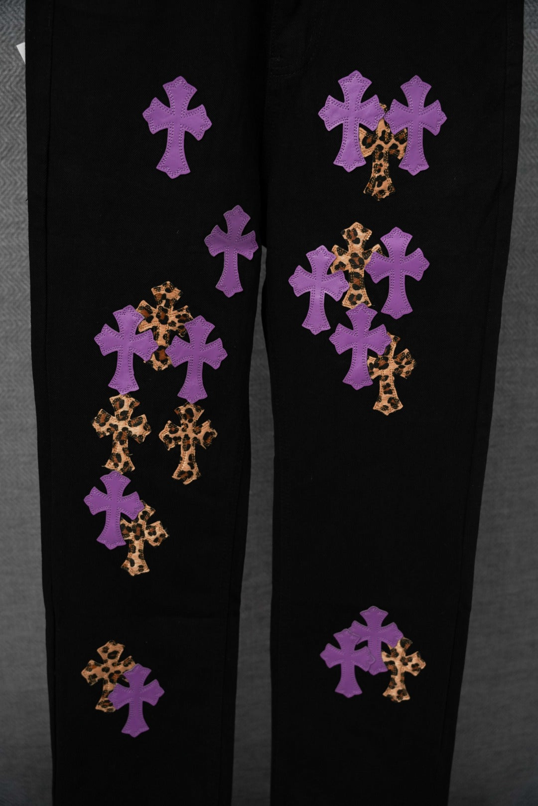 Black pants with assorted purple and gold cross patches across the legs.