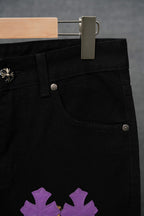 Black pants close-up: waist buttons, front pocket with purple cross patch detail.