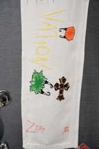 White graphic pants close-up of lower leg with yellow writing and small patches