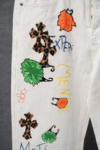White graphic pants close-up showing leopard cross, orange dress, and green patches