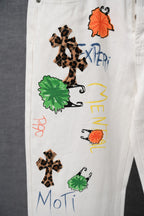 Chrome pants front close-up with multiple embroidered graphics in orange, green, and leopard