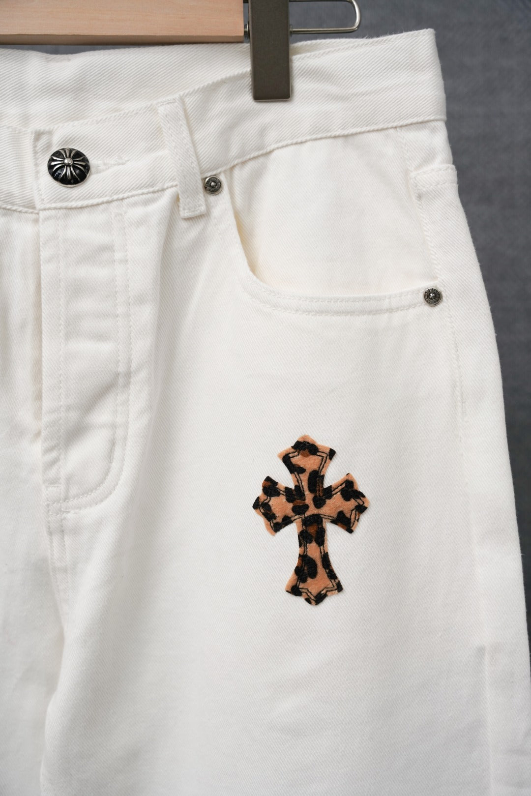 White denim pants close-up of waistband and a small leopard-print cross patch