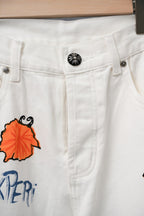 Chrome pants waistband close-up with button and colorful embroidered leaf and ink graphics