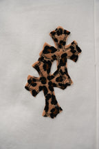 White pants with leopard-print cross appliqué on the front leg