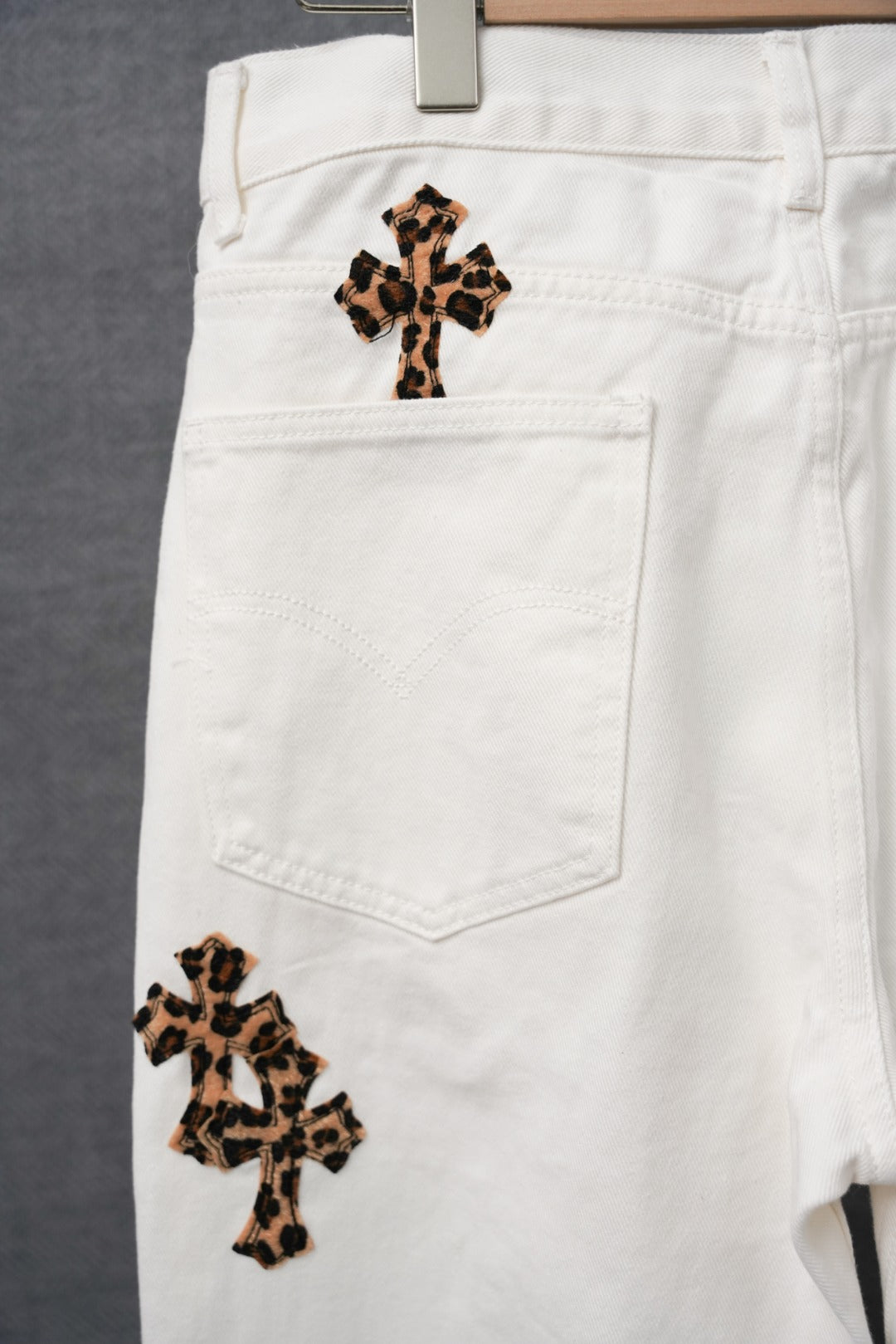 White denim pants with leopard-print cross patch on front pocket area