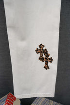White pants with leopard-print cross appliqué on the lower leg