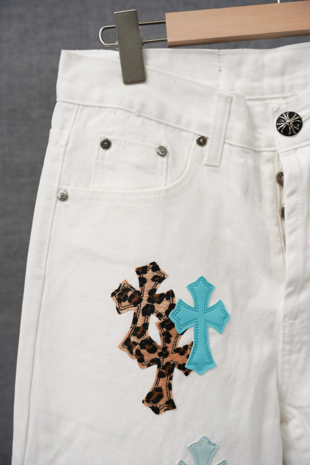 White pants with cross appliques on the front leg