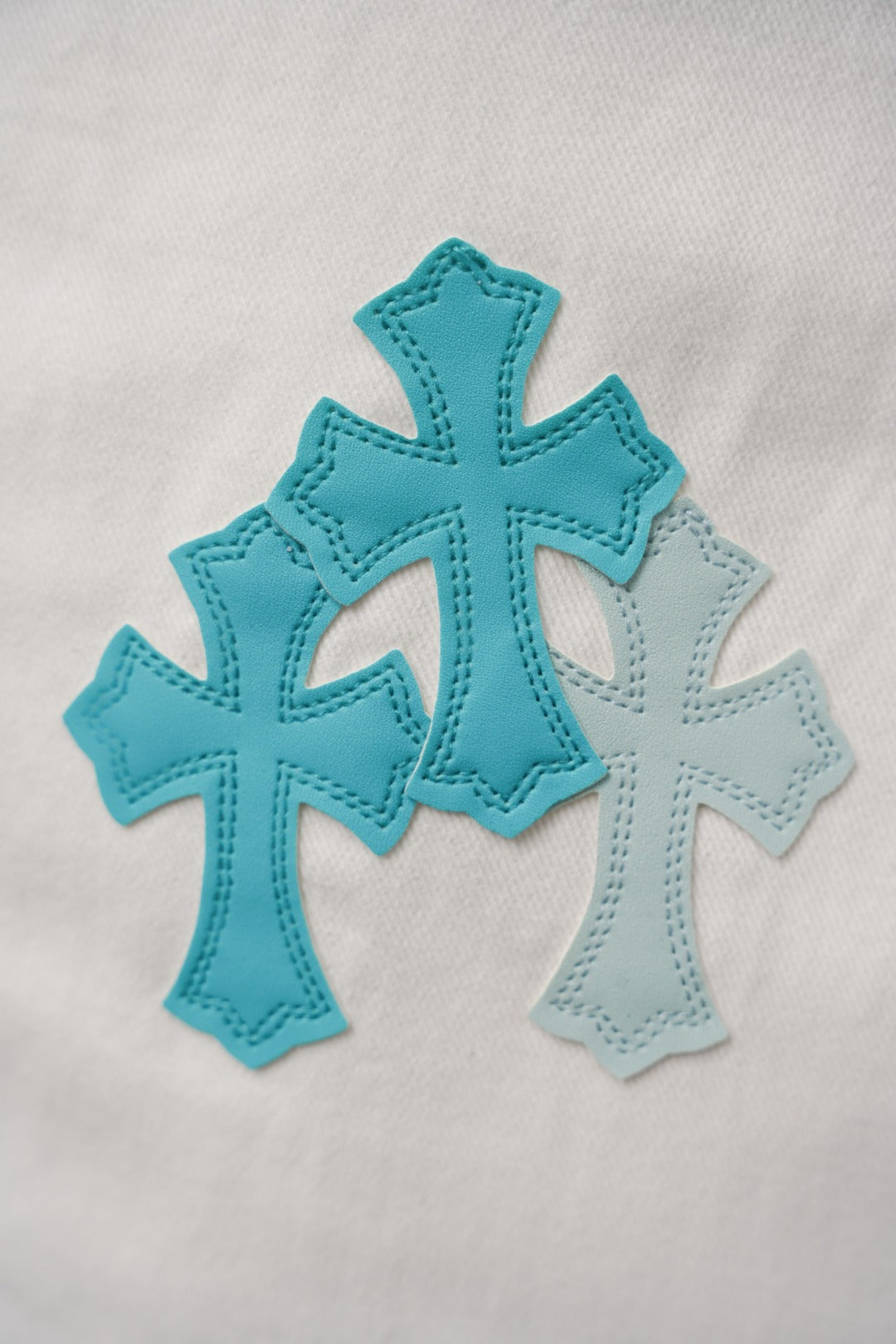 White pants with teal cross appliqué patches