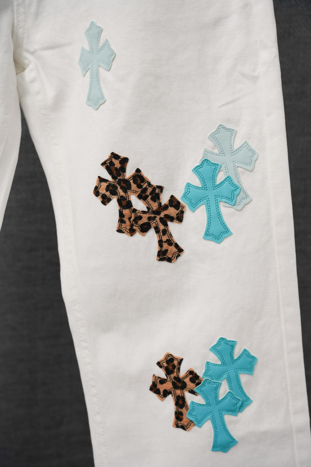 White pants with leopard and blue cross patches on the leg