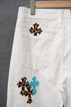 White pants with a leopard-print cross patch and teal cross accents near pocket