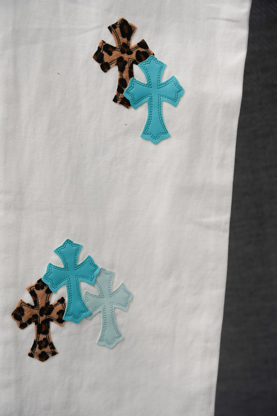 White pants with teal and leopard cross appliqué patches