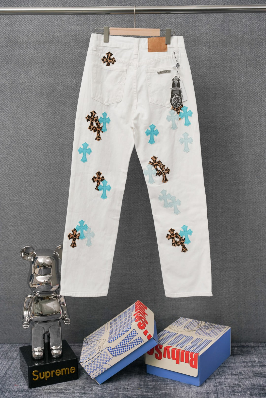 White denim pants with blue and leopard cross patches, waistband and belt loops