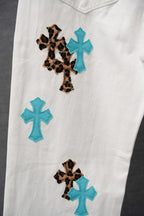 White pants with multiple teal and leopard cross patches along the front panel