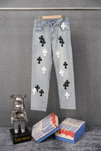 Light blue denim pants with white and black cross appliques, front view