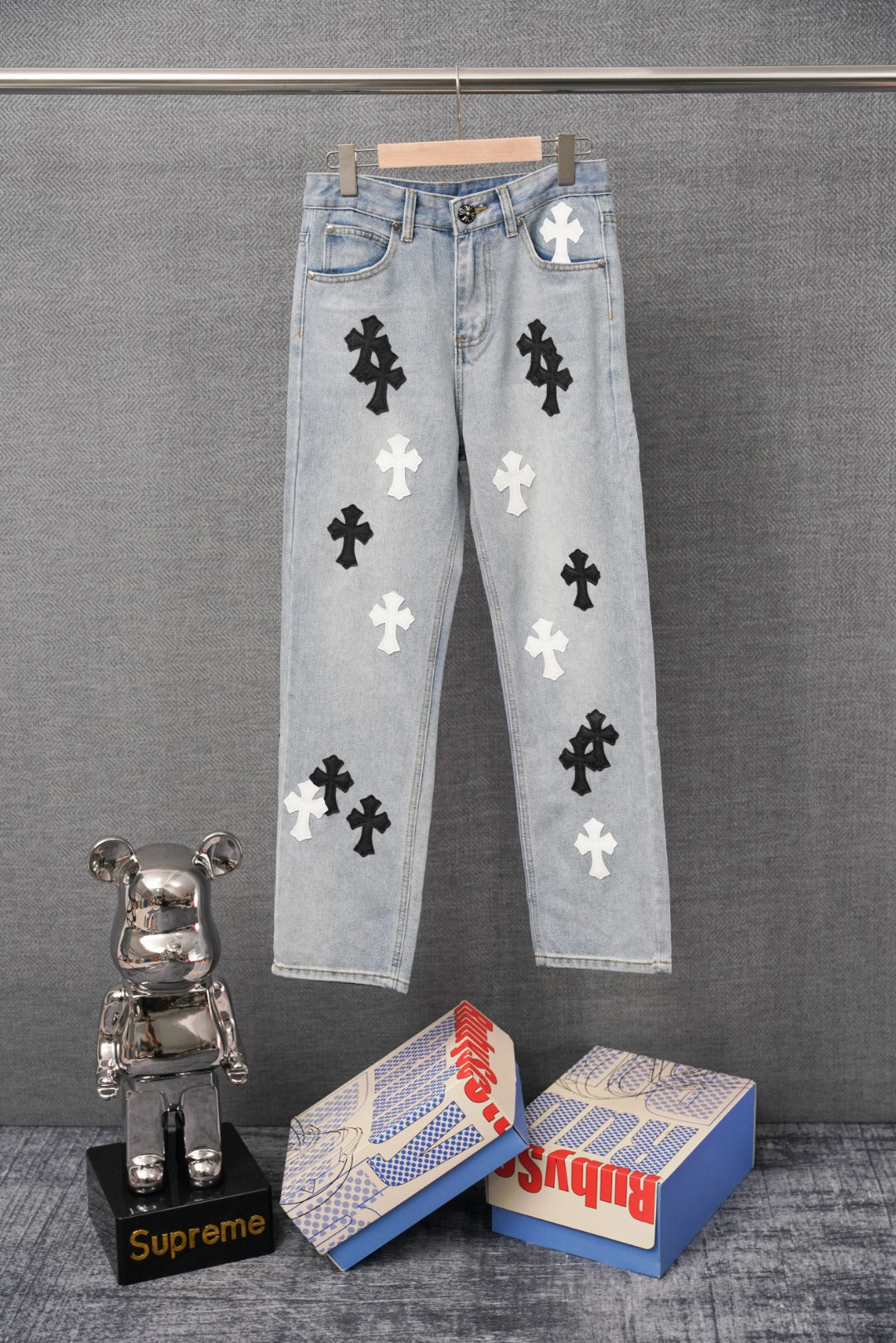 Light blue denim pants with white and black cross appliques, front view