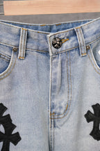 Light-wash denim pants close-up of belt loops and embroidered cross patches