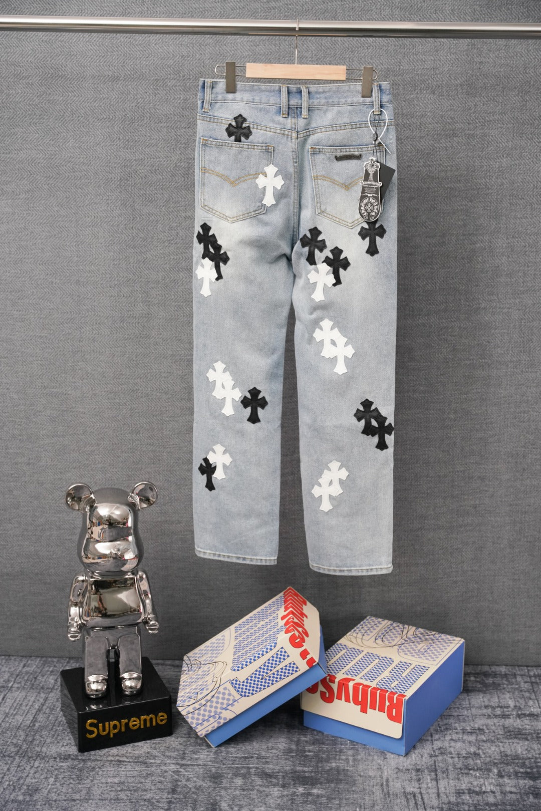 Light blue denim pants with white and black cross appliques, back view