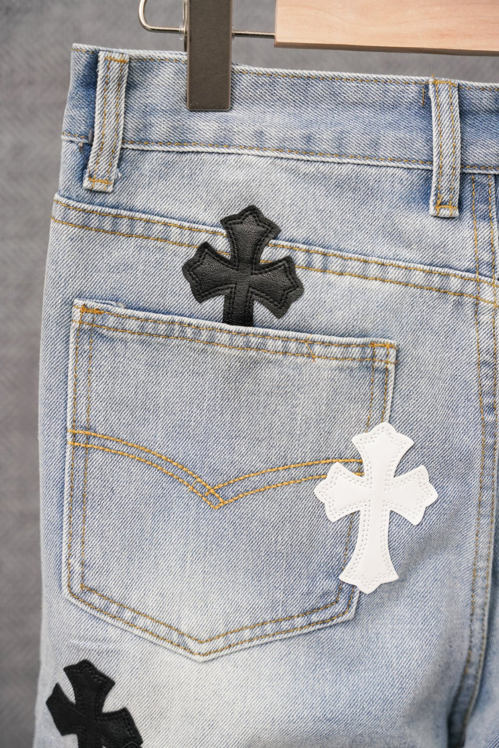 Close-up of light blue denim jeans front with cross patches and button fly