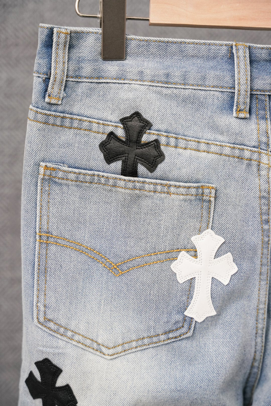 Close-up of light blue denim jeans front with cross patches and button fly