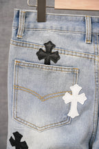 Light-wash denim pants pocket area with black and white cross patches and stitching