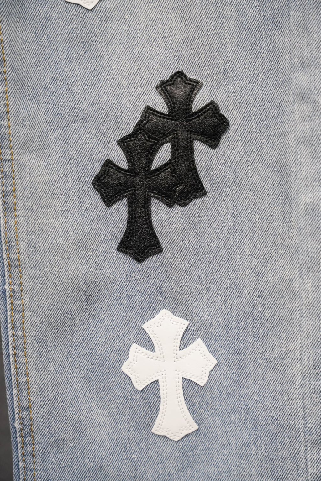 Close-up of light blue denim with black and white cross patches