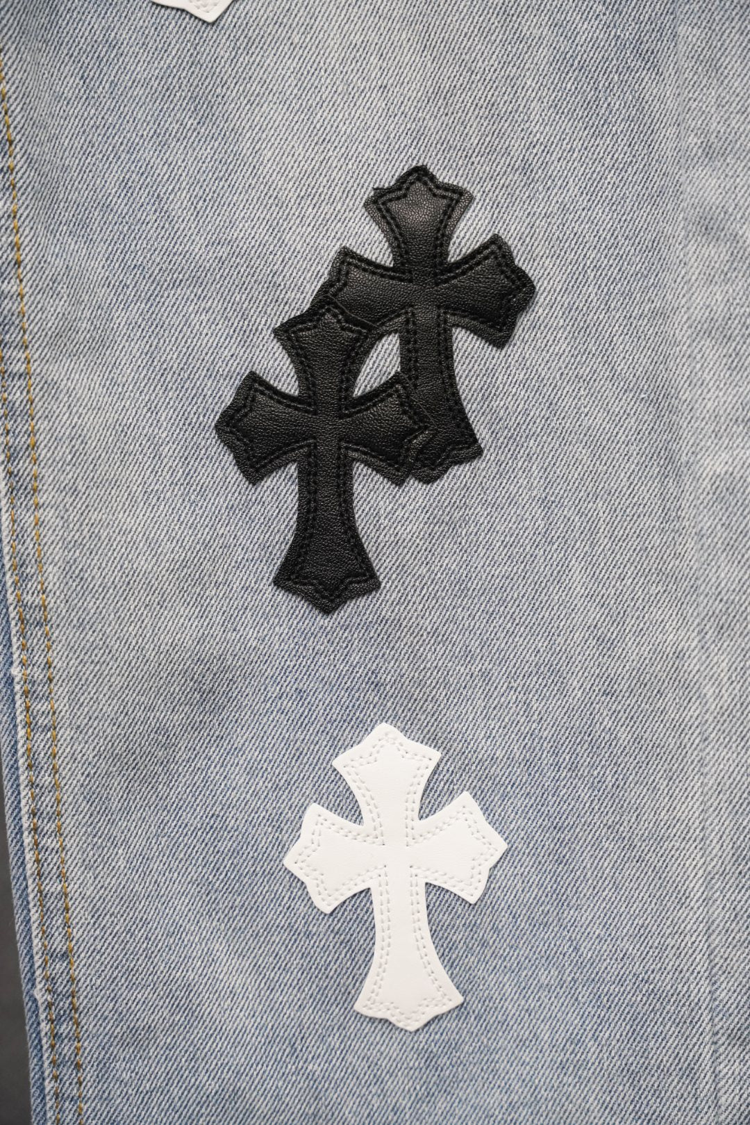 Close-up of light blue denim with black and white cross patches