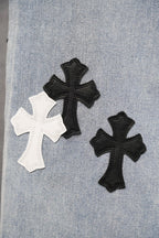 Close-up of light blue denim leg with black and white cross appliques