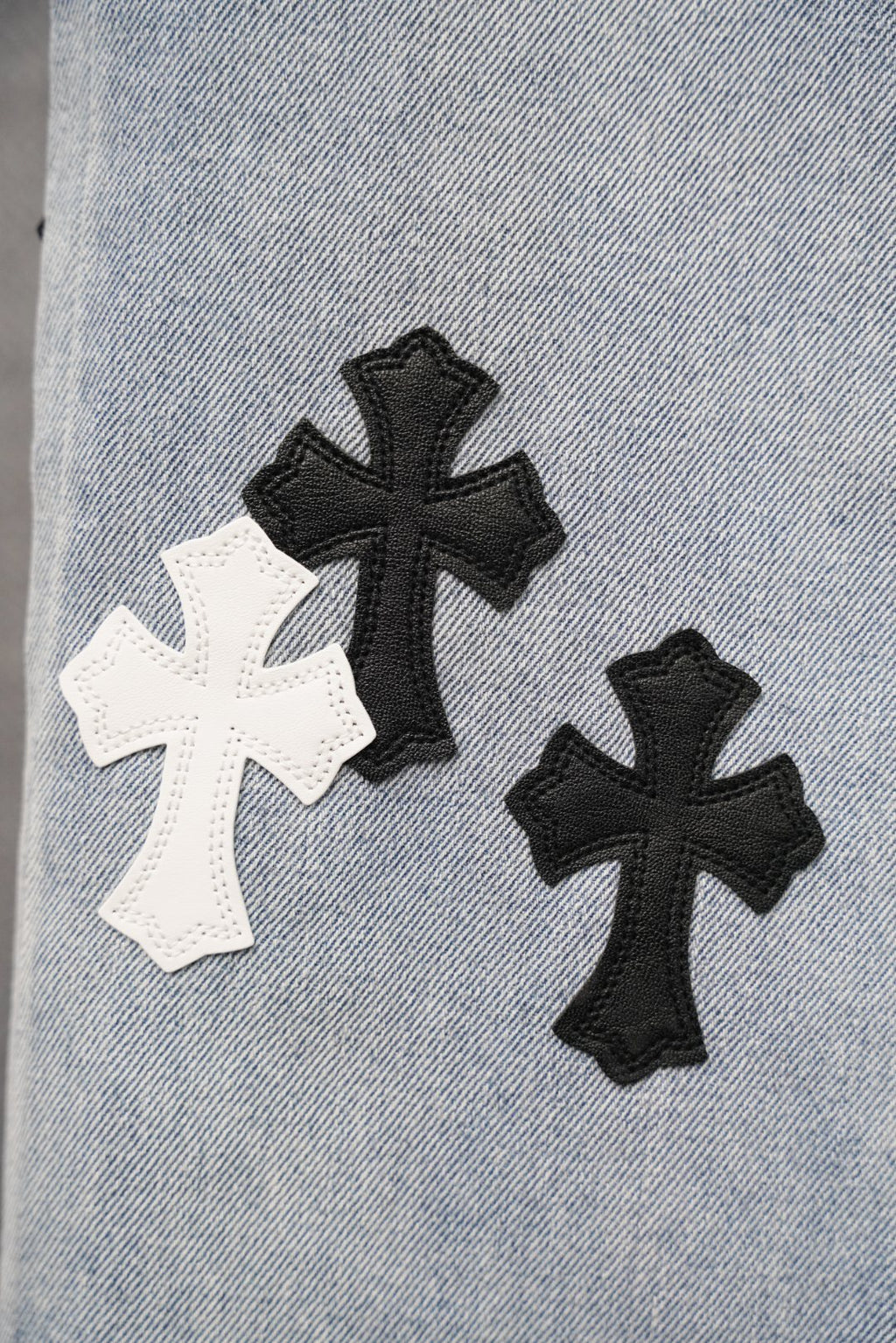 Light-wash denim fabric with black and white cross patch appliques