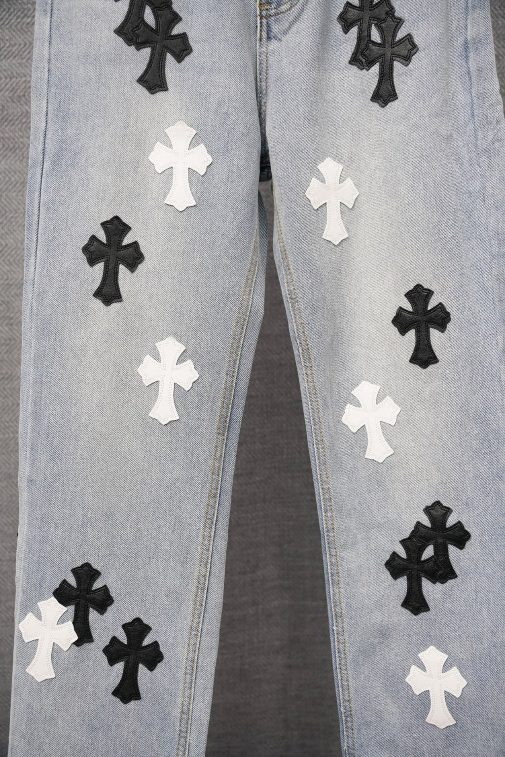 Light blue denim jeans with repeated black and white cross patches