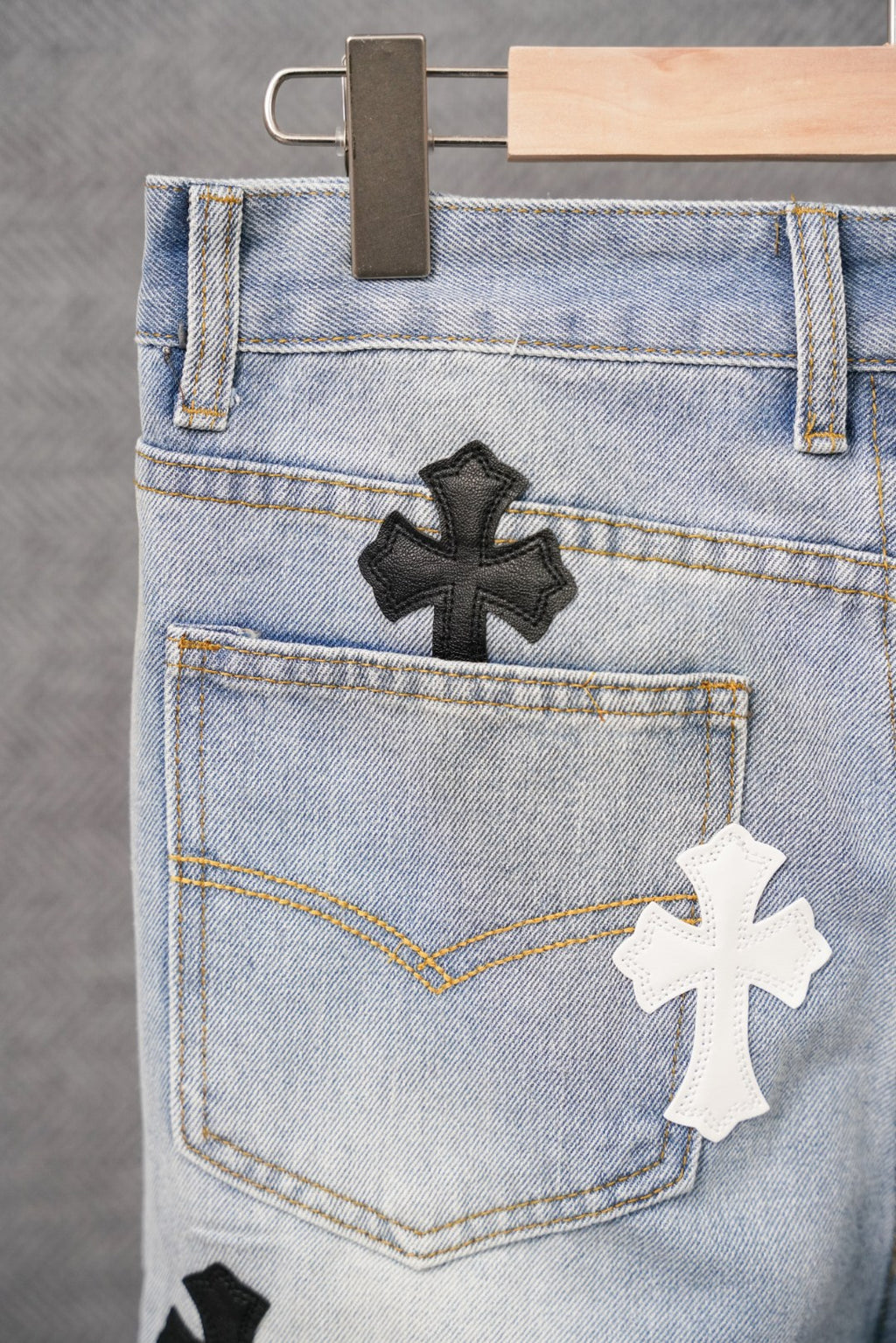 Light-wash denim pants back pocket with a black and white cross patch