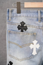 Light-wash denim pants back pocket with a black and white cross patch