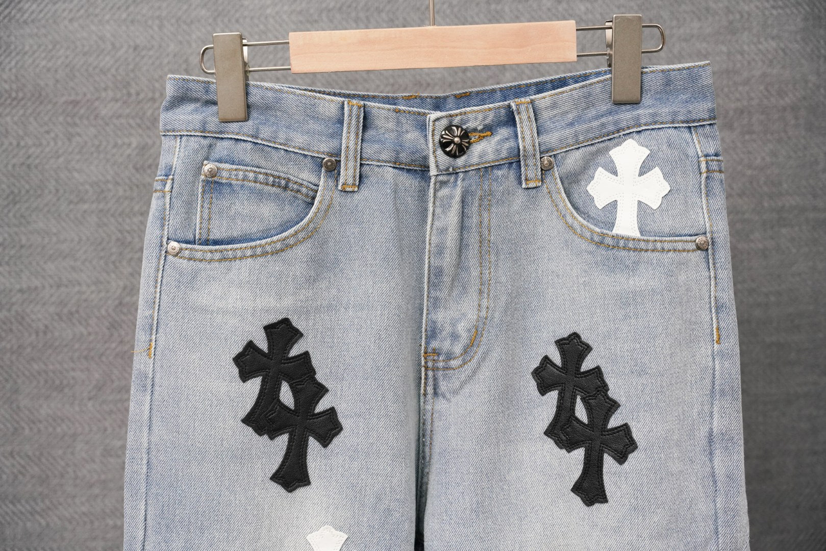 Light blue denim pants with multiple cross patches and button waistband