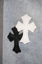 Light blue denim pants with white and black cross appliqués on fabric