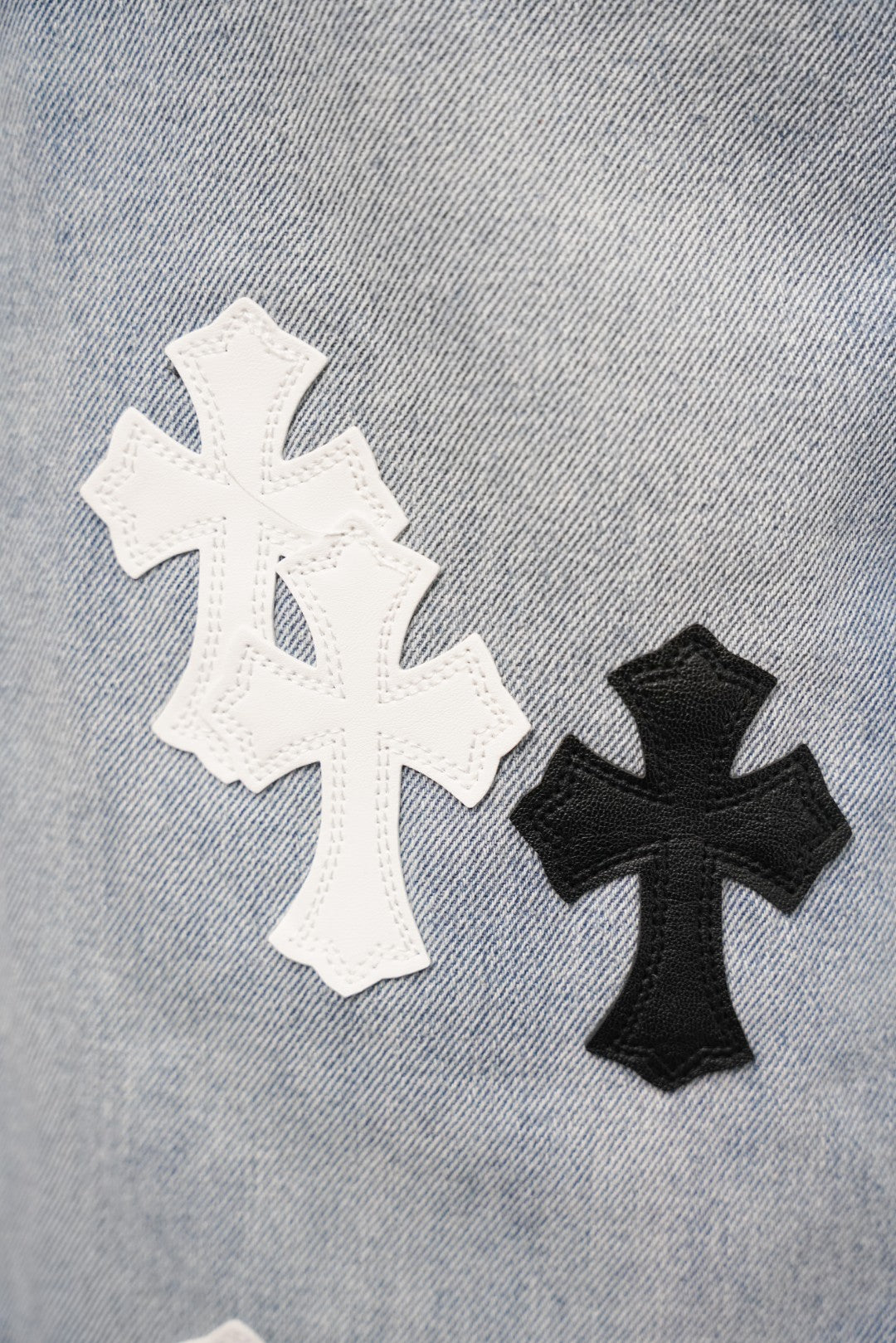 Denim pants with large white and black cross appliqué patches