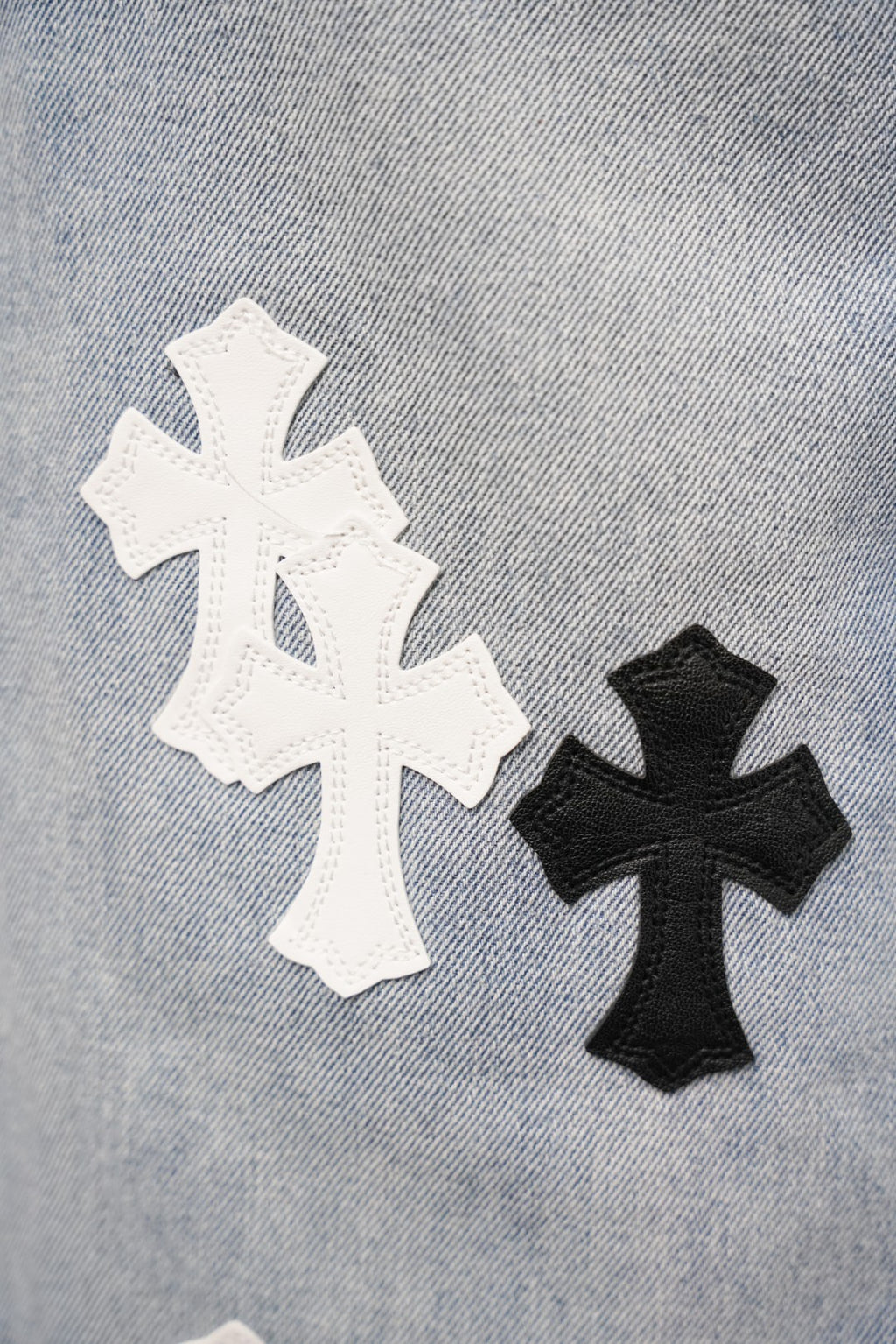 Light blue denim pants with large white and black cross patches