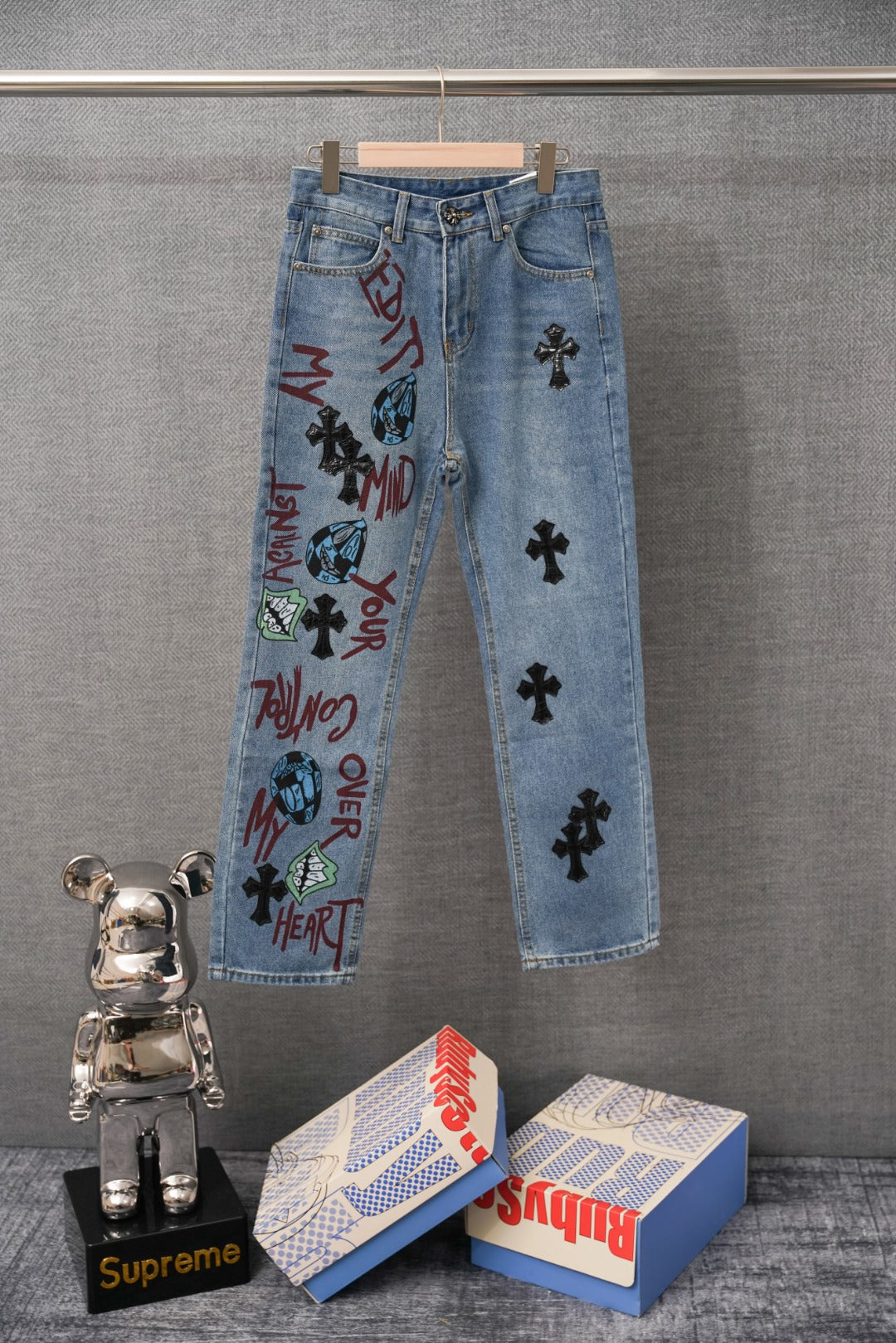 Light blue denim pants with colorful graphic print on front and patch details.